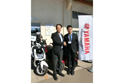中興大學代表李明安同學（右）與台灣山葉機車公司武田總經理在捐贈機車前合影
