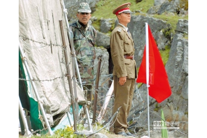 在中印邊境乃堆拉山口，一名中國邊防軍人（右）與一名印度邊防軍人隔著邊界鐵絲網值勤。（新華社）