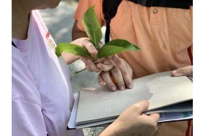 台中市立啟明學校同學嗅聞宋國彰老師採摘的植物與觸摸趙欣怡老師設計的雙視教材